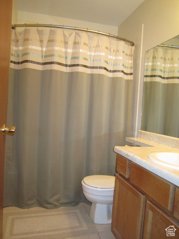 Bathroom with large vanity, tile flooring, and toilet