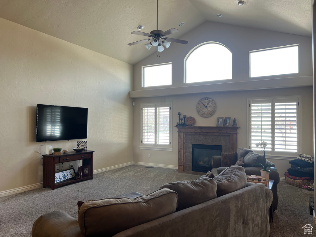 Living room with a wealth of natural light, a tiled fireplace, ceiling fan, and light colored carpet