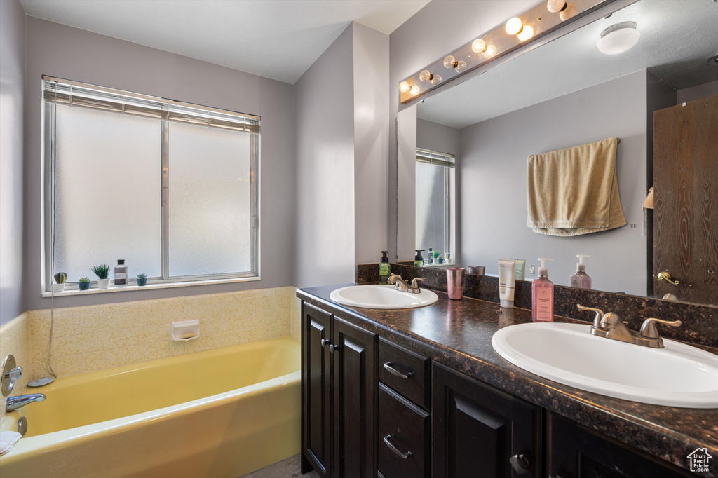 Bathroom with a bath to relax in, double sink, and vanity with extensive cabinet space