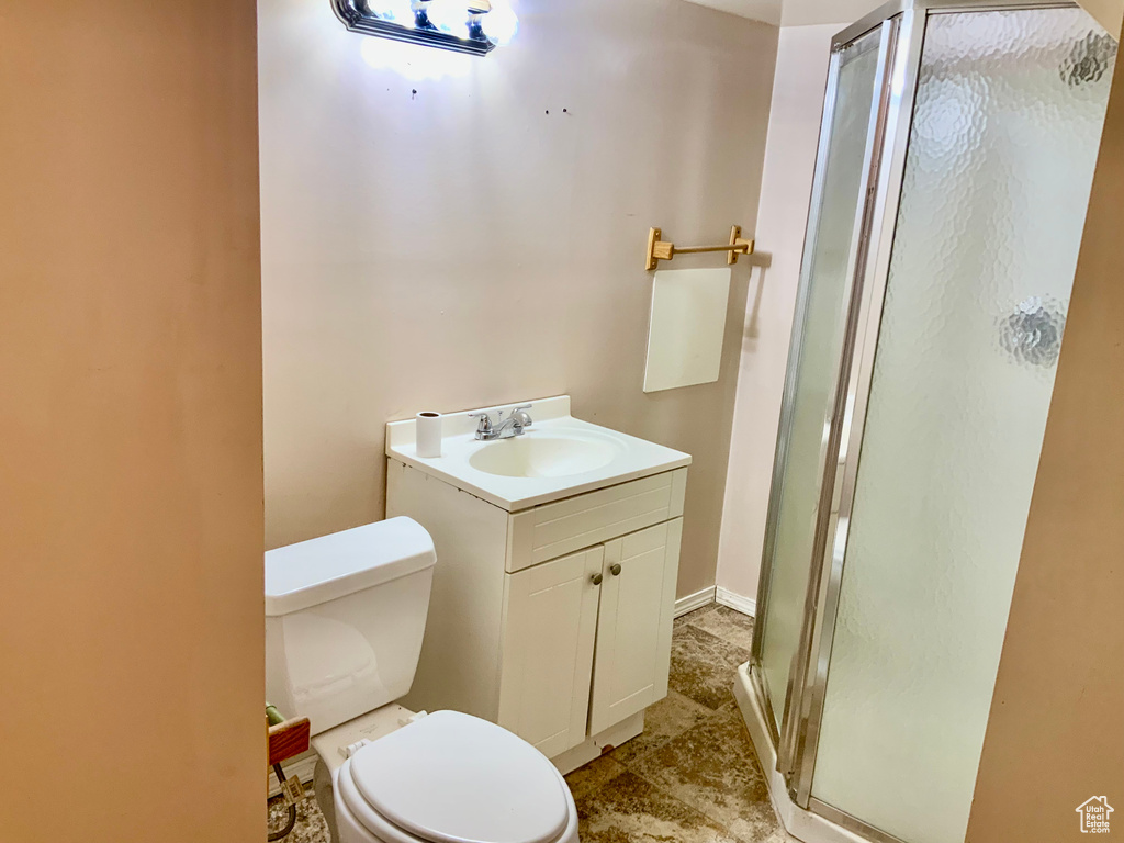 Bathroom featuring tile flooring, toilet, a shower with shower door, and vanity