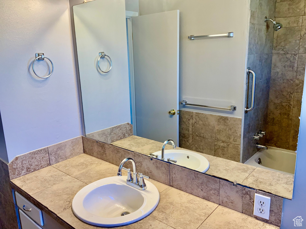 Bathroom with tile floors, vanity with extensive cabinet space, and tiled shower / bath