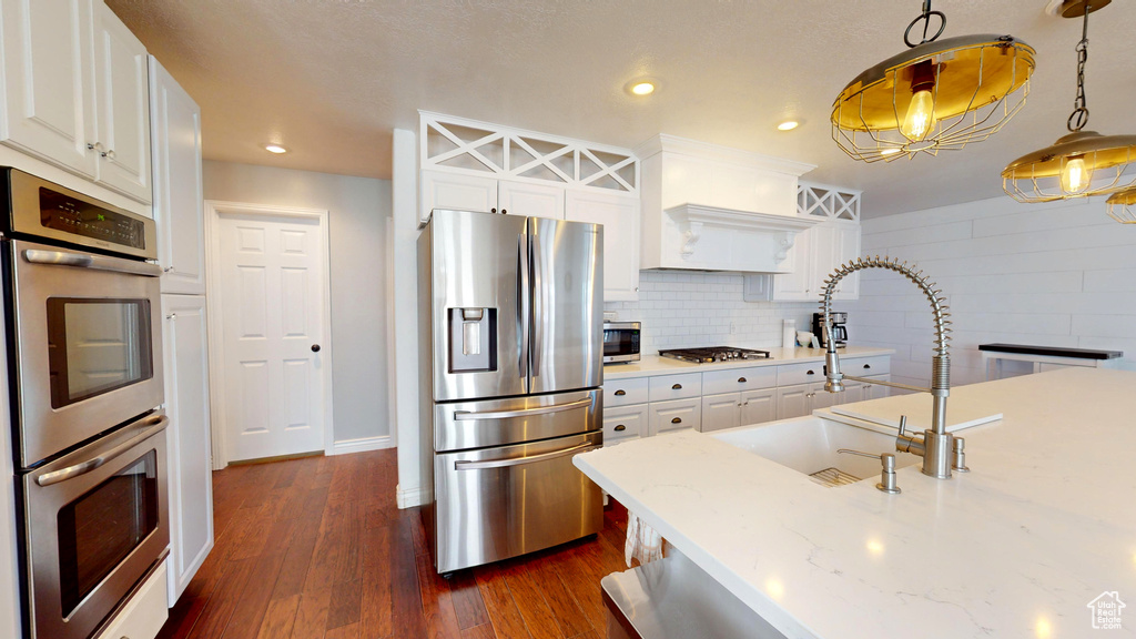 Kitchen featuring tasteful backsplash, decorative light fixtures, stainless steel appliances, and white cabinets