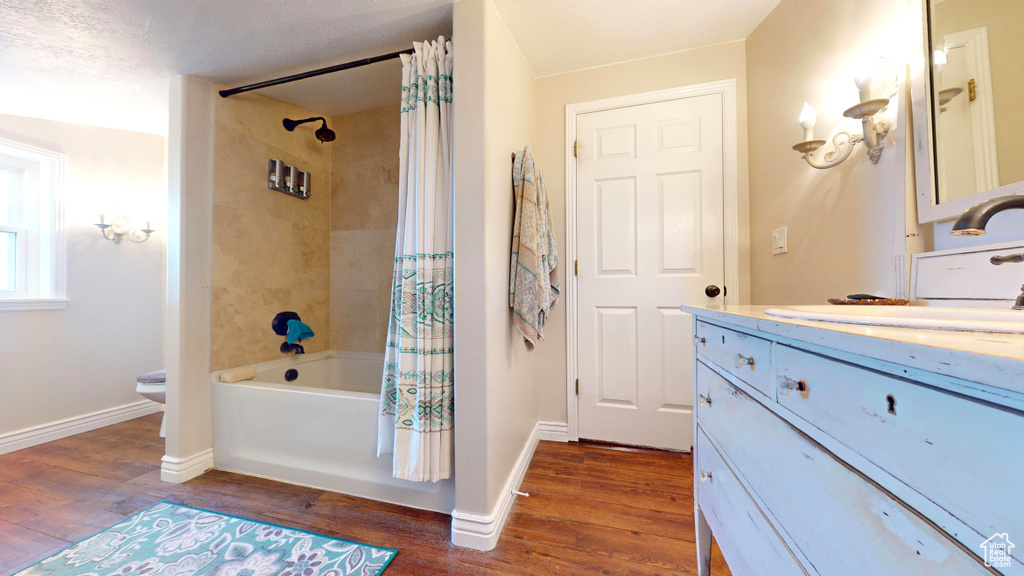Full bathroom featuring hardwood / wood-style flooring, vanity, a textured ceiling, toilet, and shower / tub combo