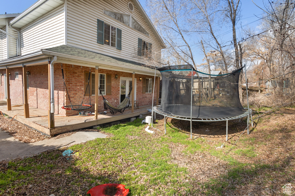 Rear view of house with a yard and a trampoline