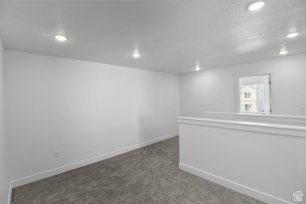 Unfurnished room featuring dark carpet and a textured ceiling
