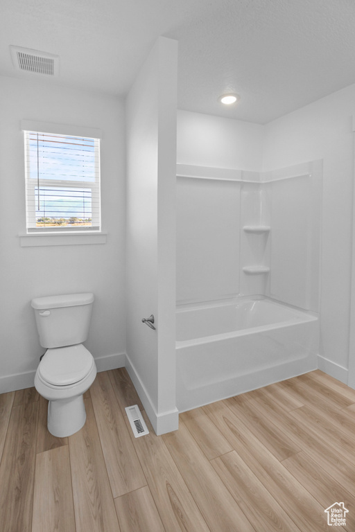 Bathroom featuring bathtub / shower combination, toilet, and hardwood / wood-style flooring
