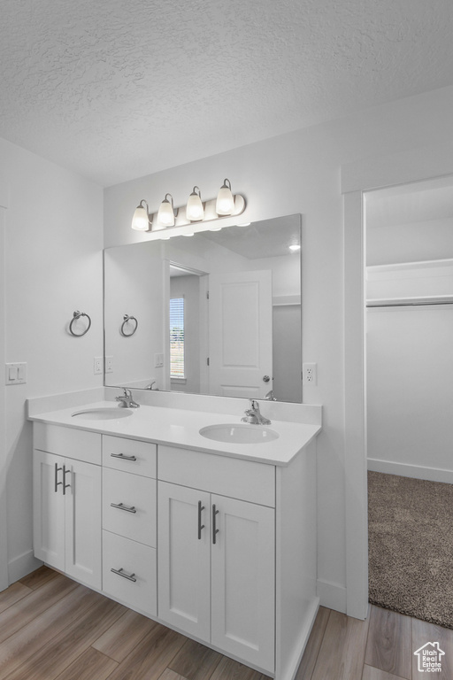 Bathroom featuring hardwood / wood-style flooring, dual vanity, and a textured ceiling