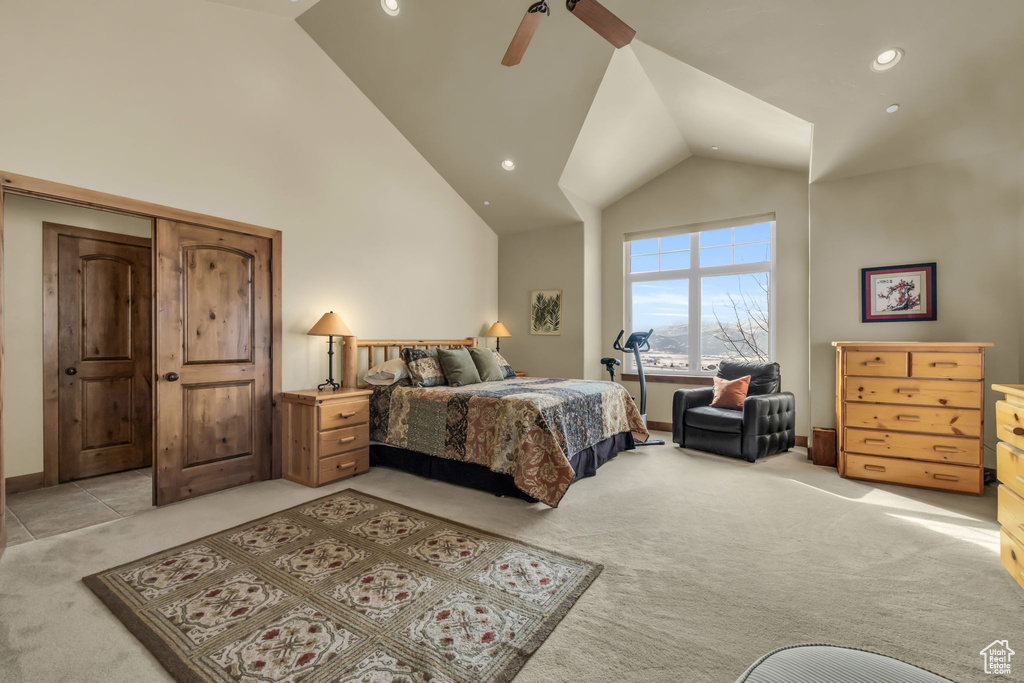 Carpeted bedroom with ceiling fan and high vaulted ceiling