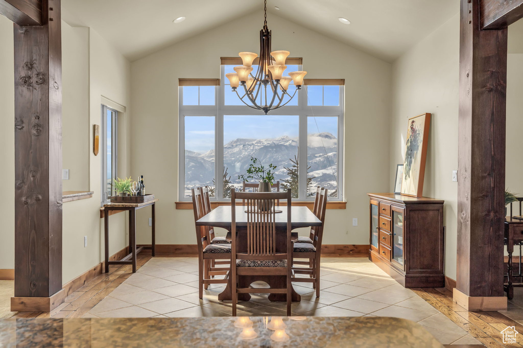 Dining area featuring an inviting chandelier, high vaulted ceiling, light tile floors, and a mountain view