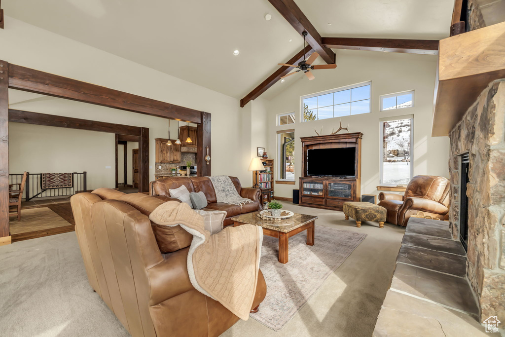 Carpeted living room with beam ceiling, a fireplace, ceiling fan, and high vaulted ceiling