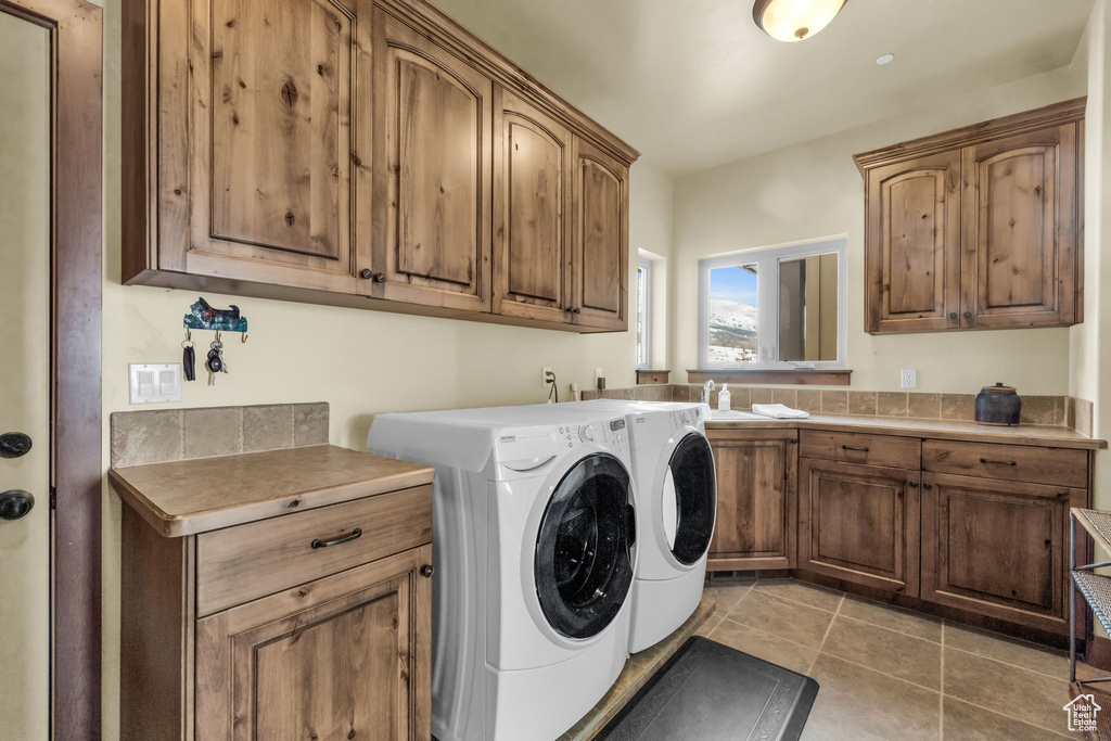 Laundry room with cabinets, light tile flooring, and independent washer and dryer