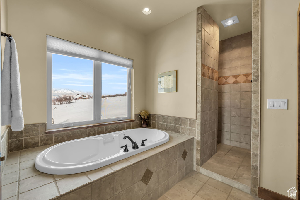 Bathroom featuring a wealth of natural light, tiled tub, and tile floors