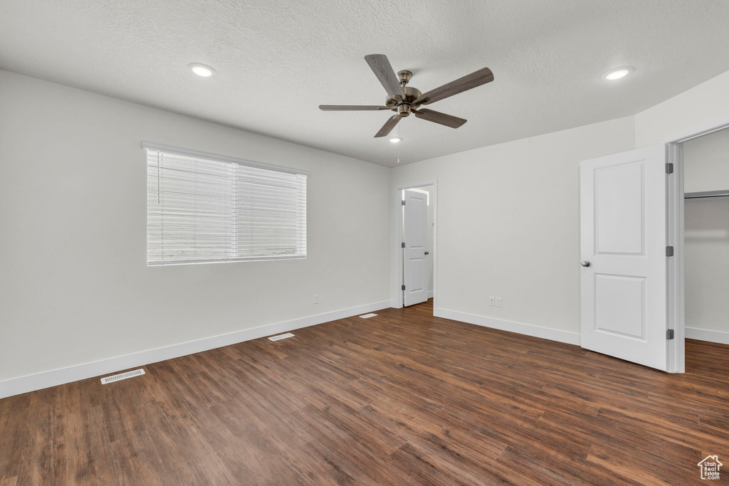 Unfurnished room featuring dark hardwood / wood-style flooring, ceiling fan, and a textured ceiling