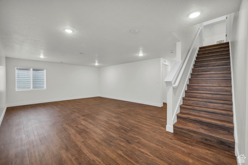 Basement with dark hardwood / wood-style flooring and a textured ceiling