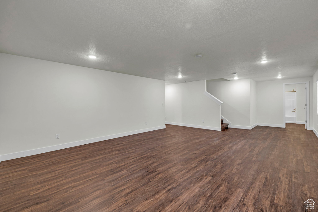 Basement with dark wood-type flooring and a textured ceiling