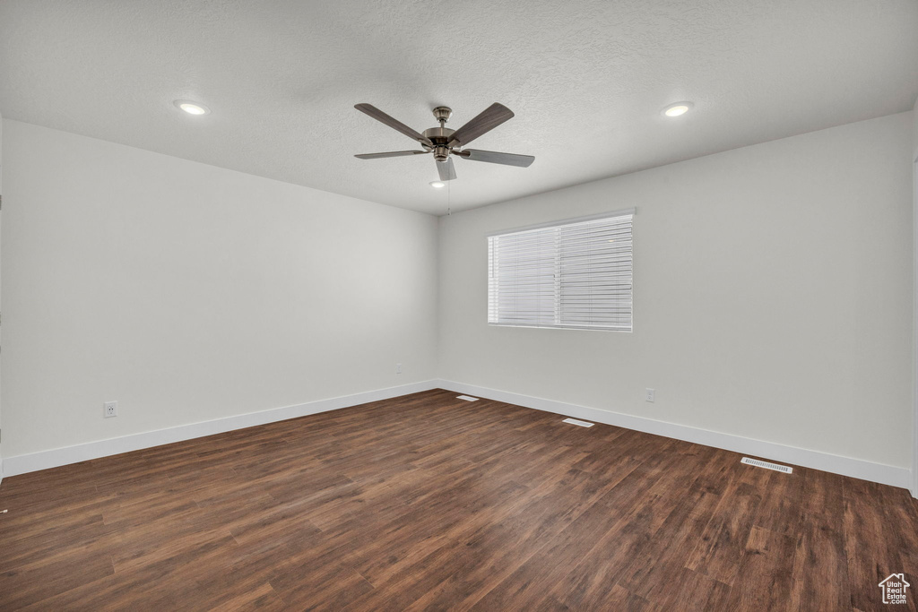 Unfurnished room with a textured ceiling, ceiling fan, and dark hardwood / wood-style flooring