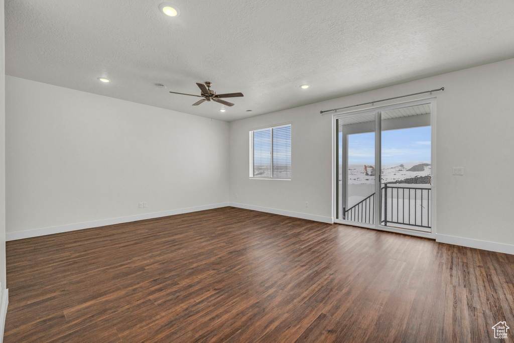 Empty room with ceiling fan, dark hardwood / wood-style floors, and a textured ceiling