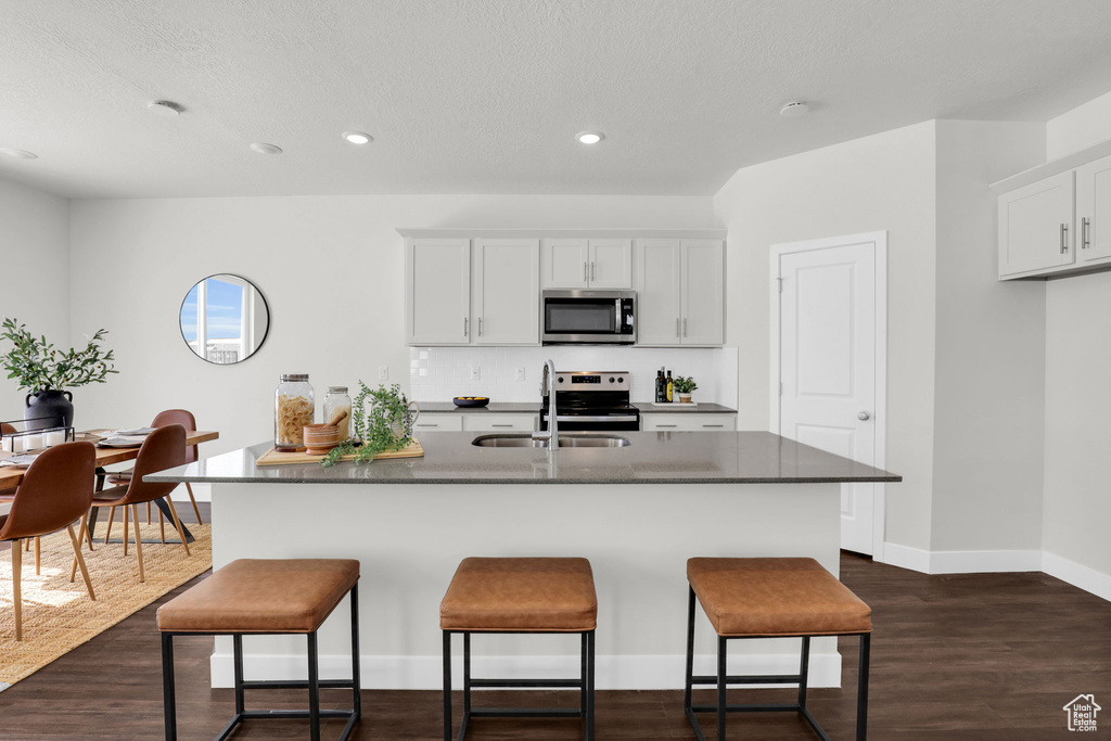 Kitchen featuring white cabinetry, appliances with stainless steel finishes, dark wood-type flooring, and sink