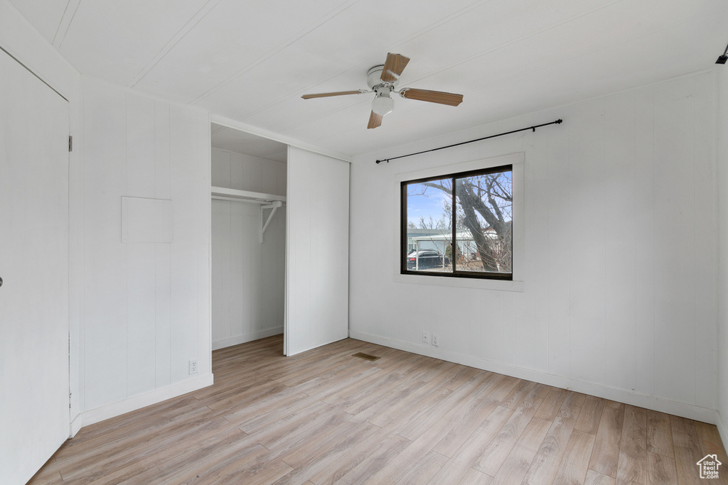 Unfurnished bedroom with ceiling fan, a closet, and light wood-type flooring