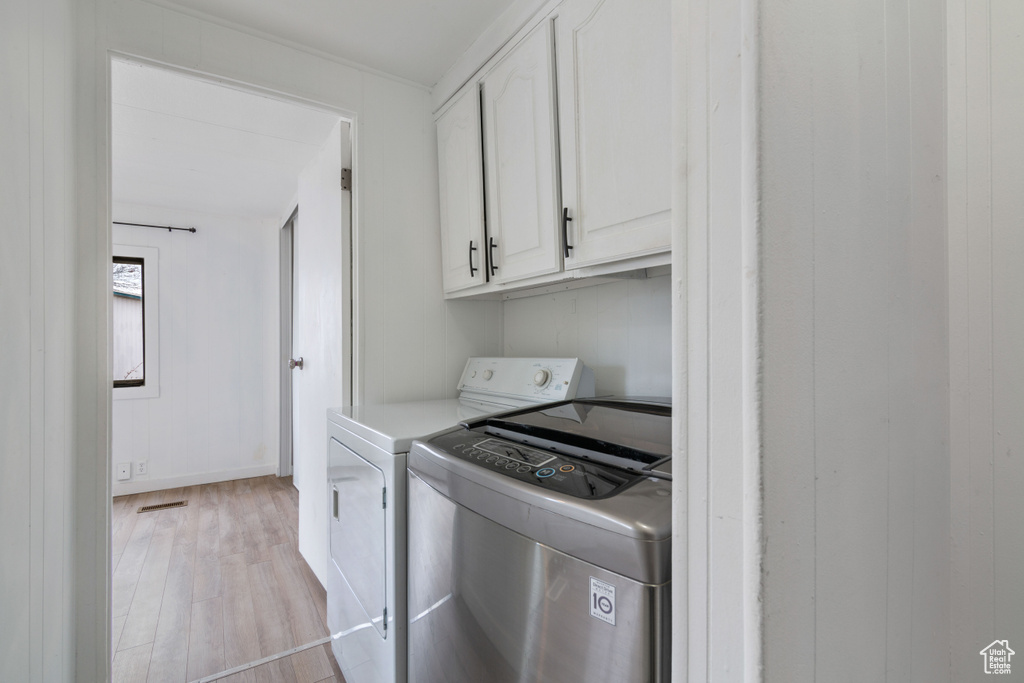 Laundry room featuring cabinets, light hardwood / wood-style flooring, and independent washer and dryer