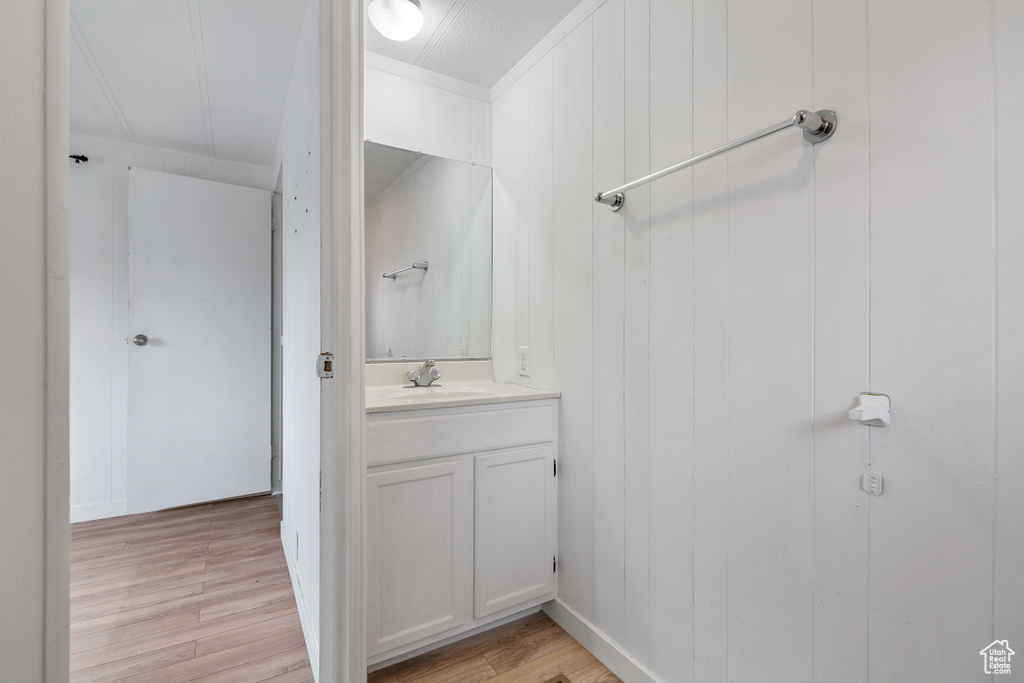 Bathroom with vanity, ornamental molding, and wood-type flooring