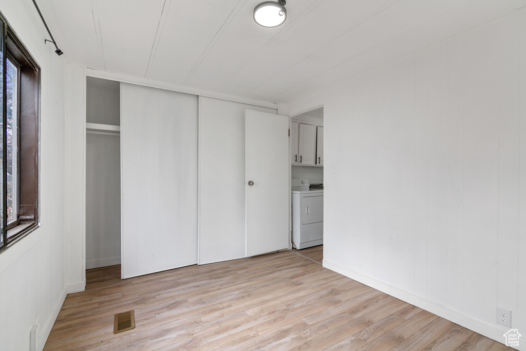 Unfurnished bedroom with a closet, light wood-type flooring, and washing machine and dryer