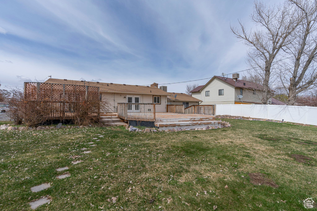 Back of property featuring a wooden deck and a yard