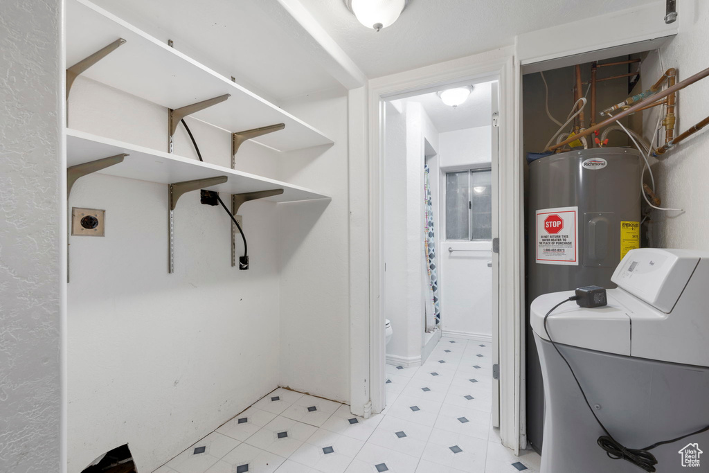 Laundry room featuring electric water heater, light tile floors, and washer / clothes dryer