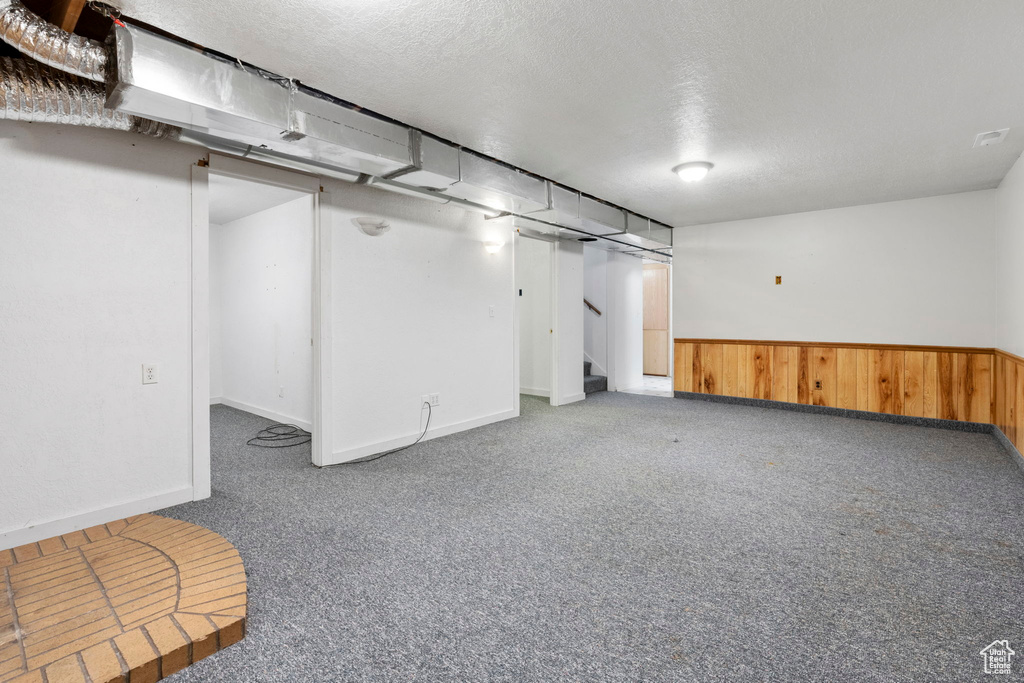 Basement featuring dark carpet and a textured ceiling