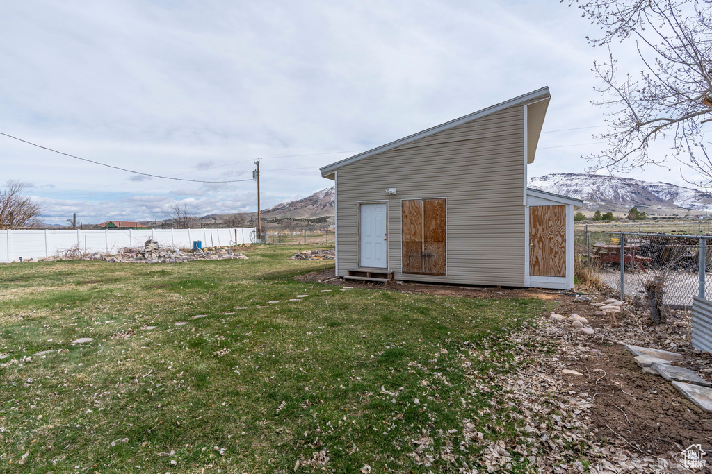 Back of property with a lawn, a mountain view, and a storage unit