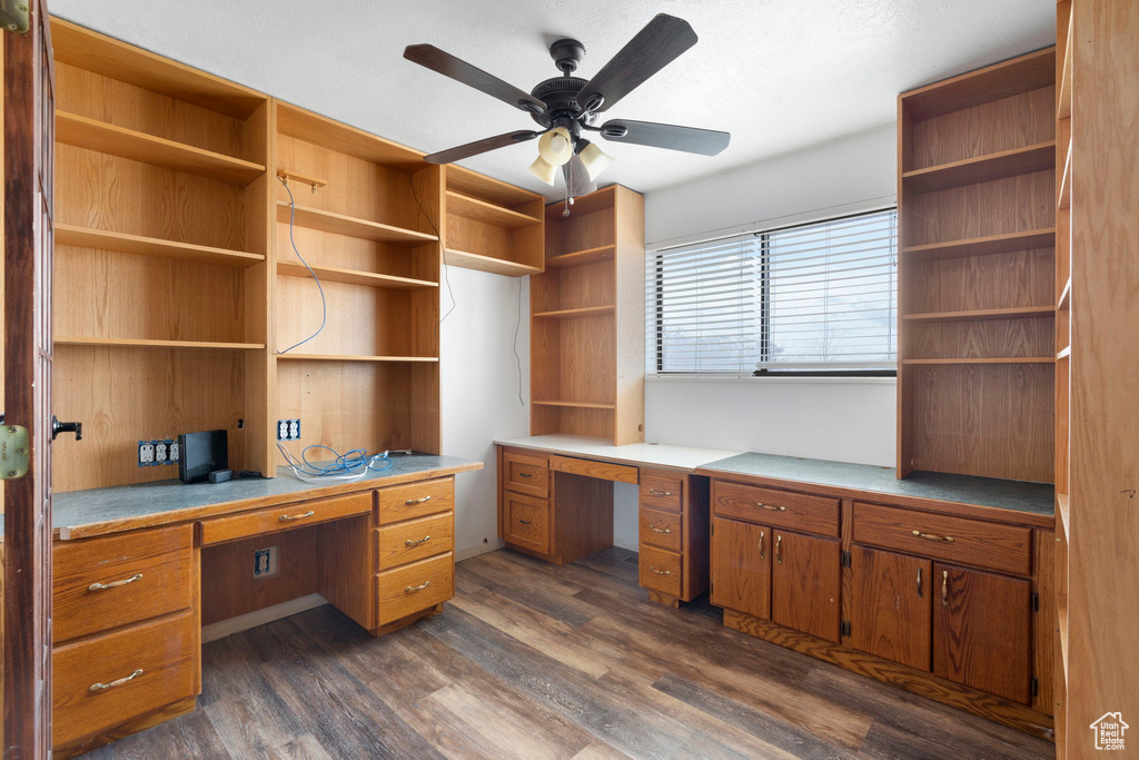 Office featuring ceiling fan, dark wood-type flooring, and built in desk