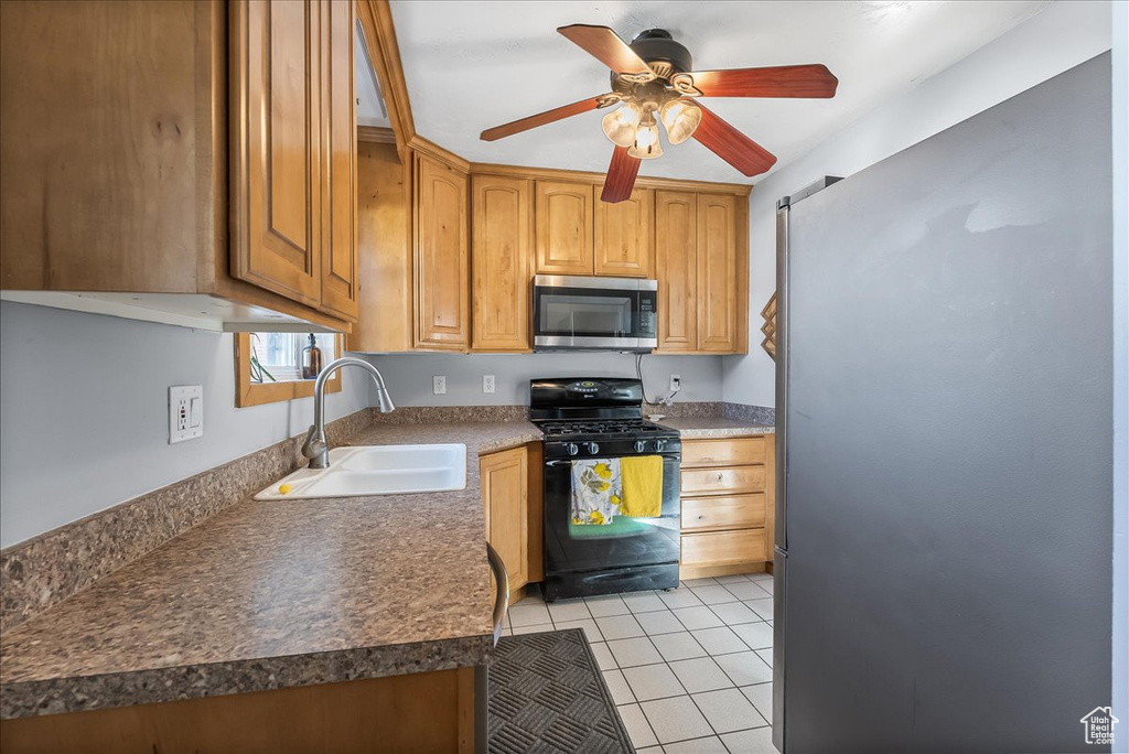Kitchen with sink, appliances with stainless steel finishes, light tile floors, and ceiling fan