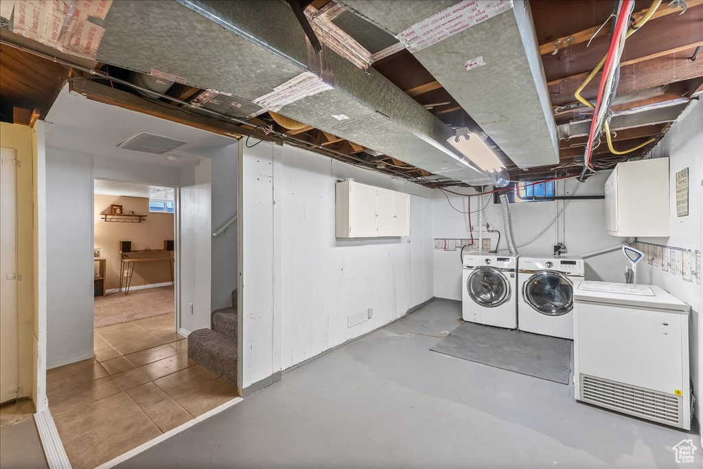 Basement with light tile flooring and washer and dryer