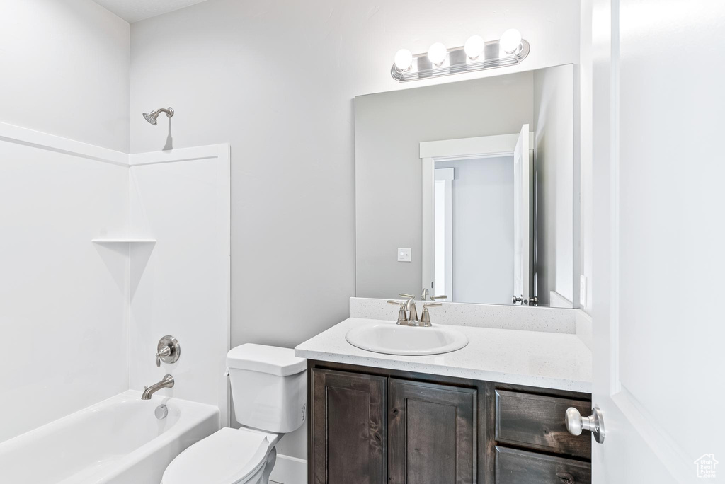 Full bathroom featuring toilet, vanity with extensive cabinet space, and  shower combination