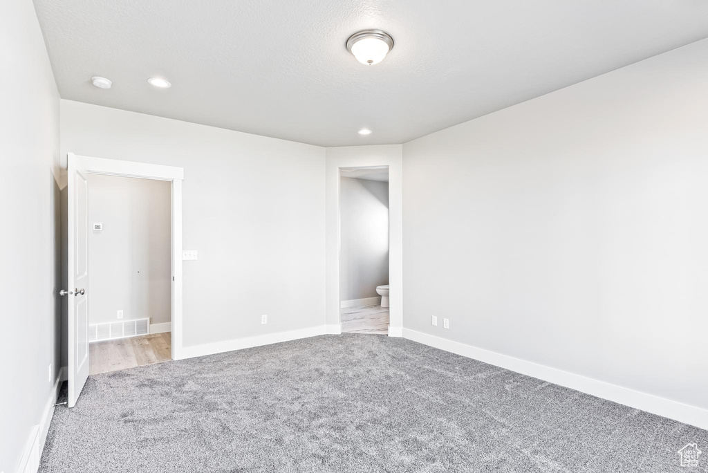 Unfurnished bedroom featuring connected bathroom and light colored carpet