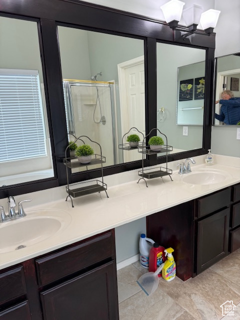 Bathroom with dual sinks, tile flooring, and vanity with extensive cabinet space