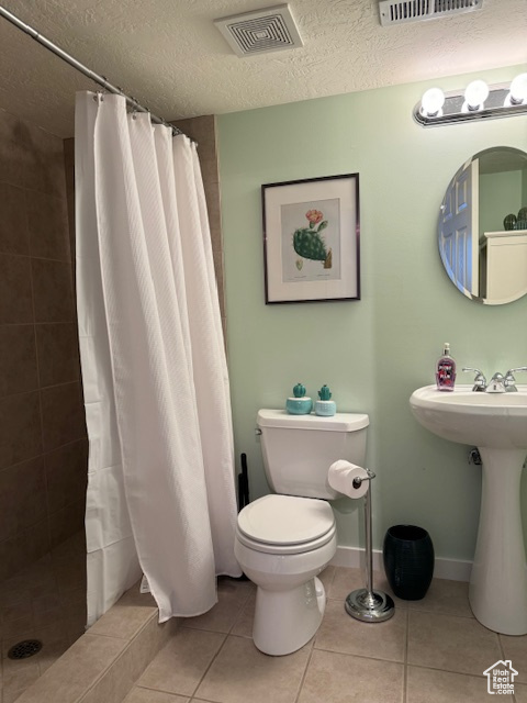 Bathroom featuring a textured ceiling, tile floors, a shower with shower curtain, and toilet