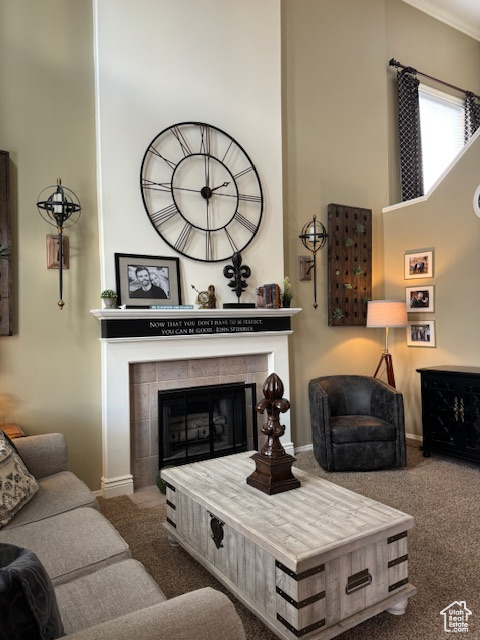 Living room featuring dark colored carpet, a fireplace, crown molding, and a towering ceiling