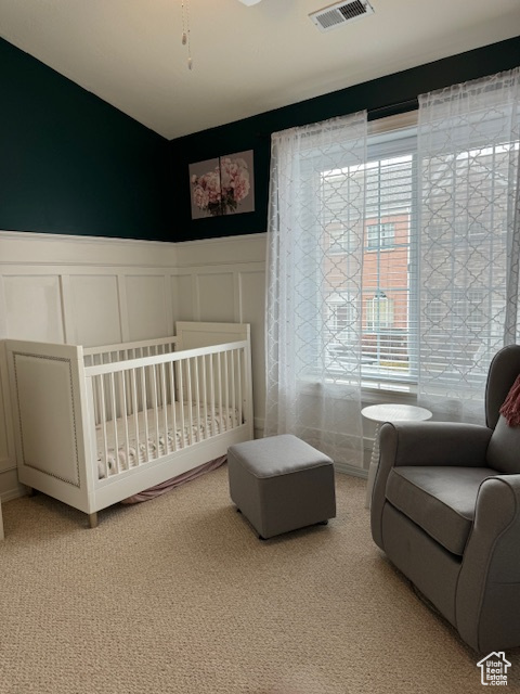 Bedroom with a crib and light carpet