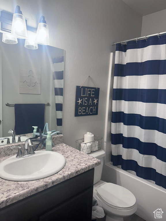 Full bathroom featuring vanity with extensive cabinet space, toilet, and shower / bath combo with shower curtain