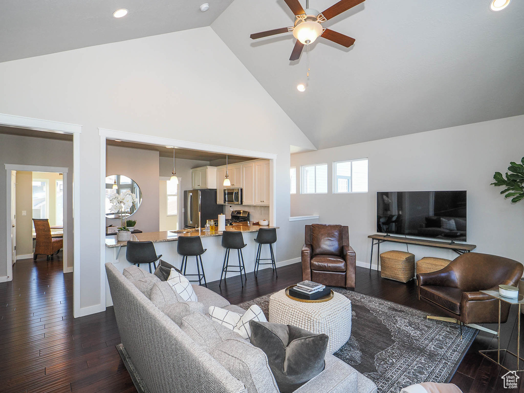 Living room with ceiling fan, dark hardwood / wood-style floors, and high vaulted ceiling
