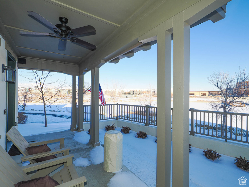 Snow covered patio featuring covered porch and ceiling fan