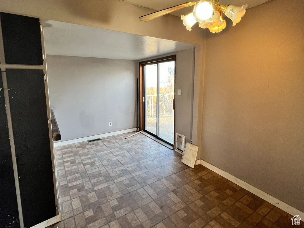 Empty room featuring ceiling fan and dark tile flooring