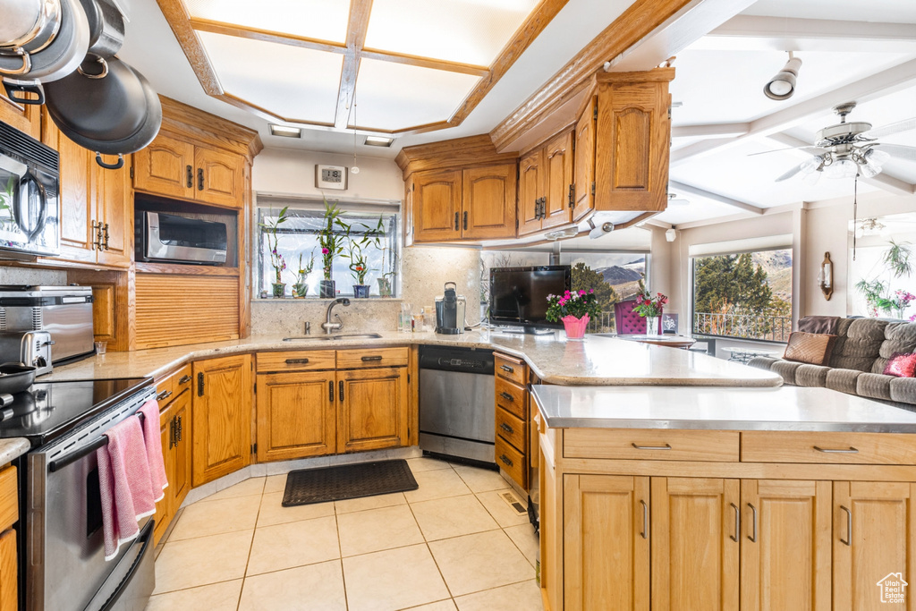 Kitchen featuring stainless steel appliances, backsplash, light tile flooring, sink, and ceiling fan