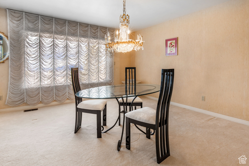 Carpeted dining room with a chandelier and a wealth of natural light