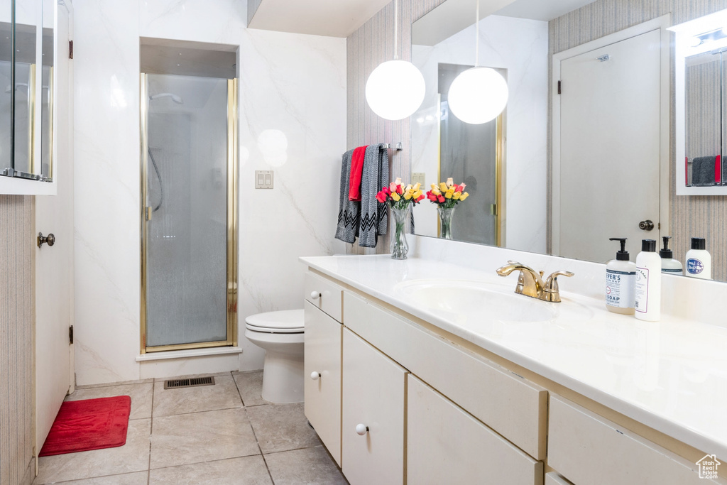 Bathroom featuring an enclosed shower, large vanity, tile floors, and toilet