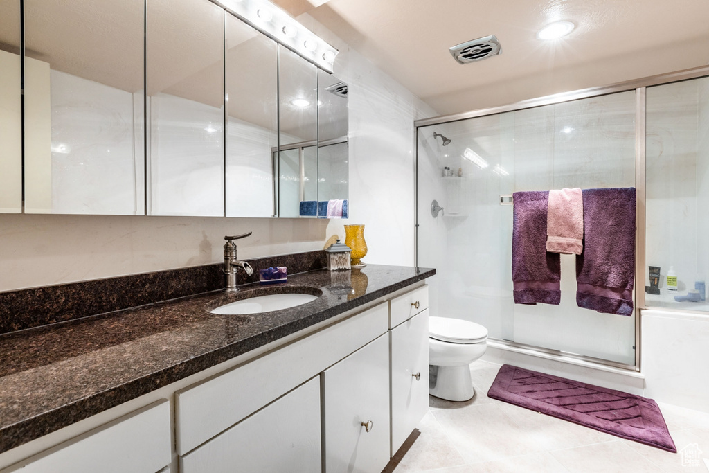 Bathroom featuring tile floors, vanity, walk in shower, and toilet