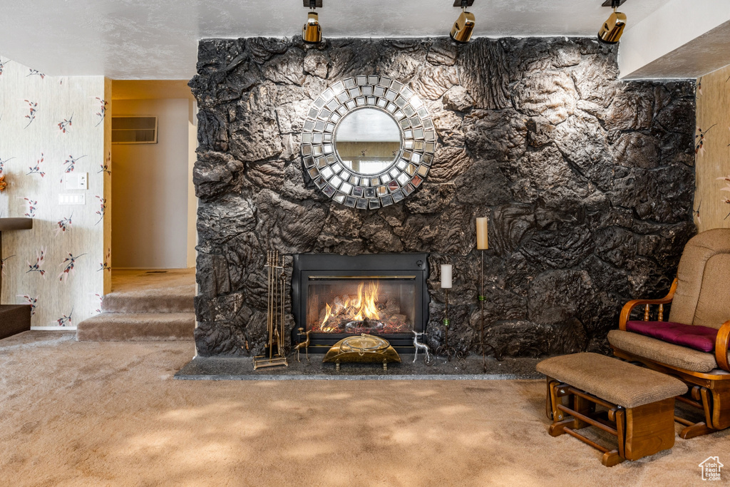 Room details featuring a stone fireplace, carpet floors, and a textured ceiling