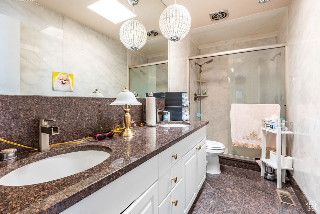 Bathroom featuring double sink, toilet, large vanity, and tile flooring