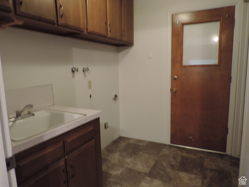 Laundry area featuring cabinets, hookup for a washing machine, dark tile floors, and sink